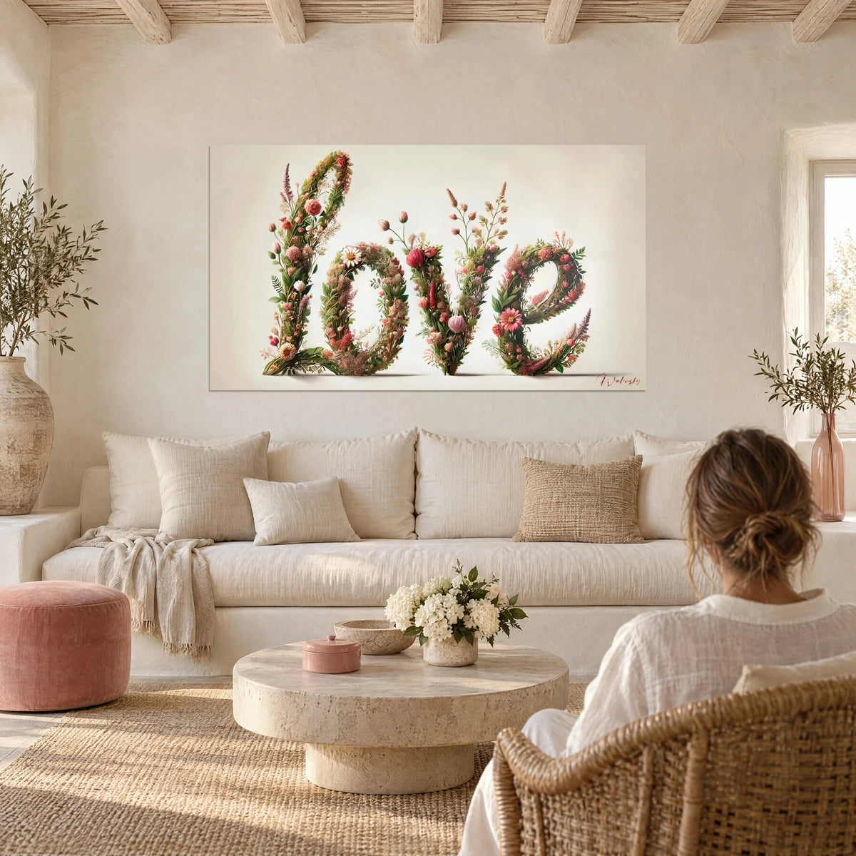 Gemälde mit Schriftzug Love aus geflochtenen leuchtend rosa Rosen und grünem Blattwerk über einem Sofa in einem hellen Wohnzimmer