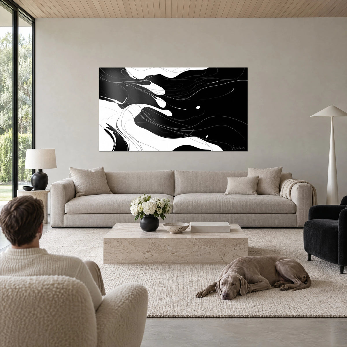 Tableau abstrait de volutes noires et blanches aux filets argentés fins, dos à dos avec un Weimaraner, au-dessus d'un canapé dans un salon lumineux
