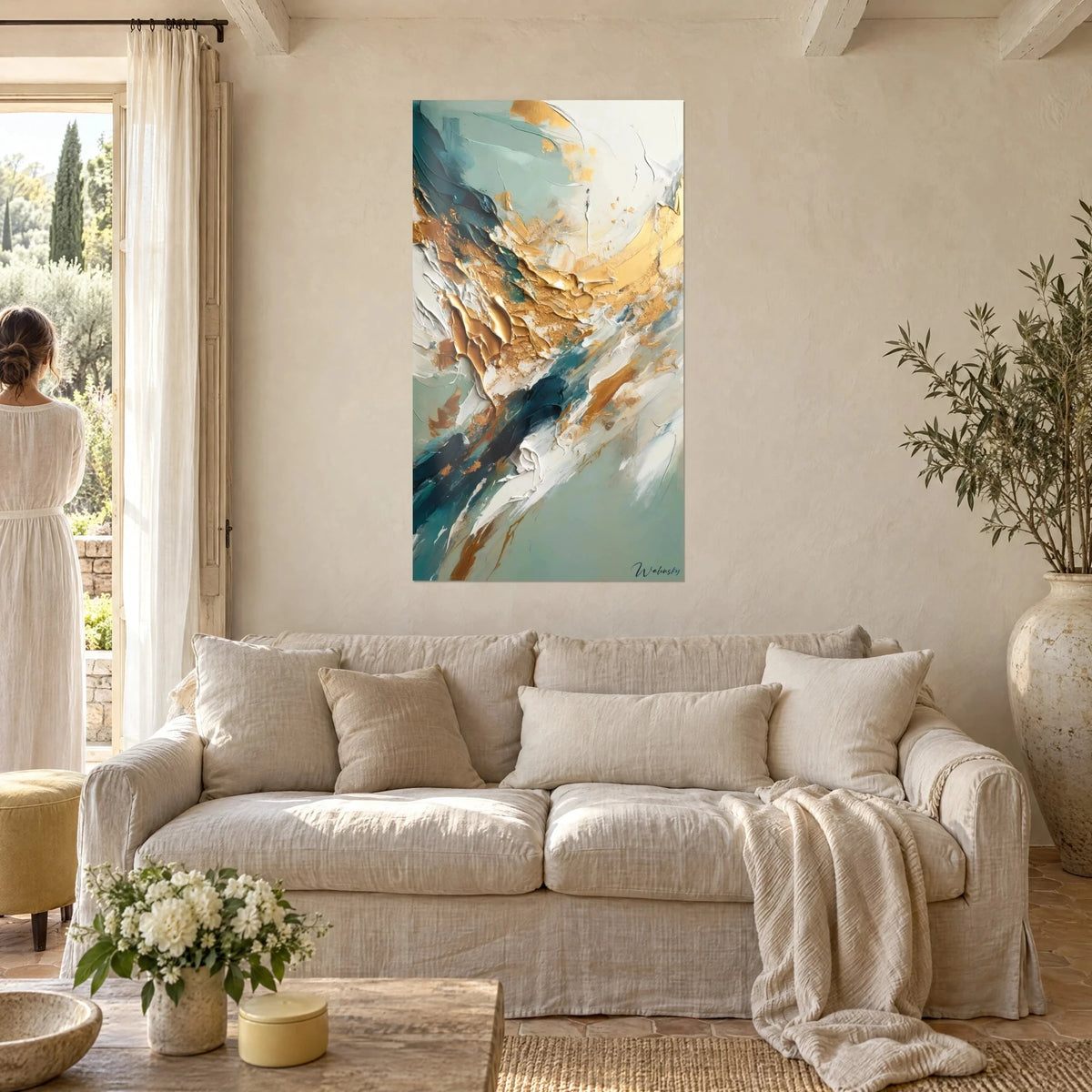 Quadro Dipinto astratto con impasti oro e bianco su fondo verde acqua, donna di spalle, sopra un divano in un soggiorno luminoso