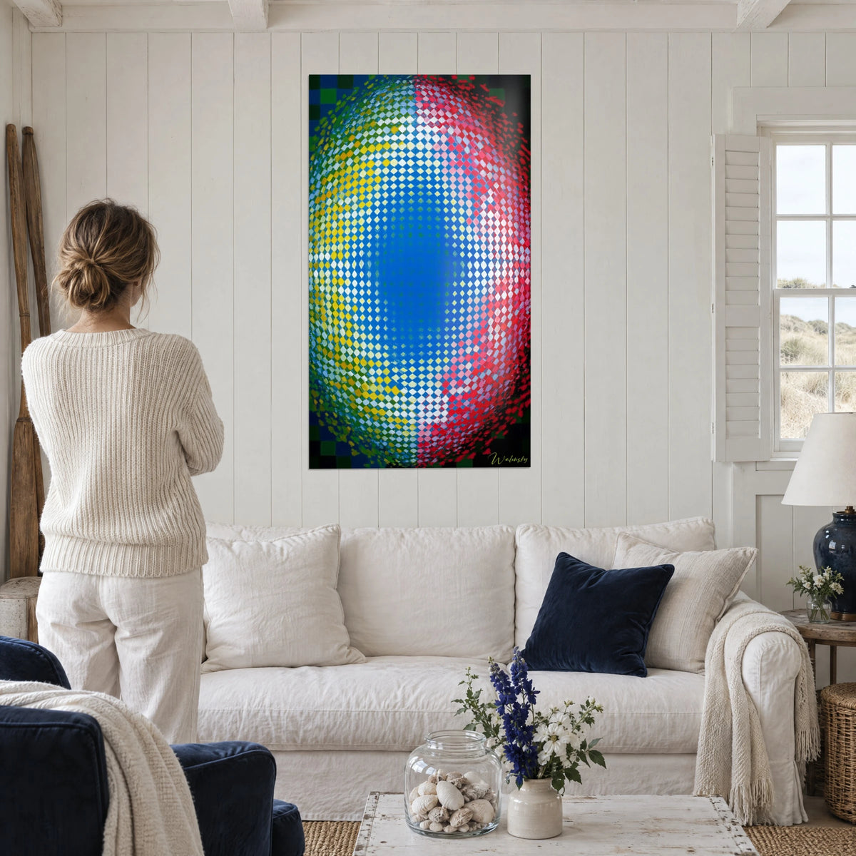 Cuadro oval hipnótico de rombos azules, amarillos y rojos, visto de espaldas encima de un sofá en un salón luminoso