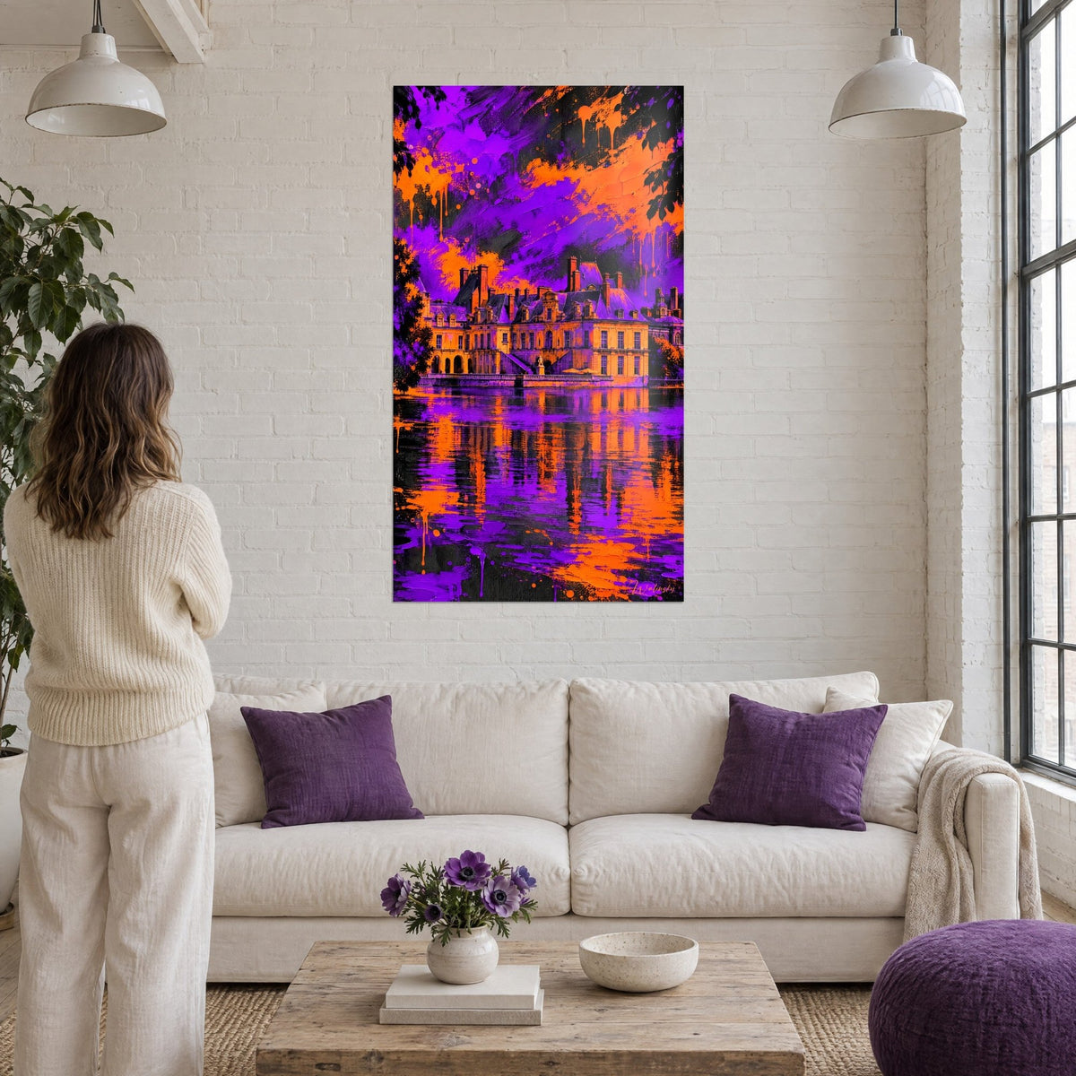 Quadro castello con tetti in ardesia riflesso in uno stagno, colature arancioni su un cielo viola, sopra un divano in un soggiorno luminoso