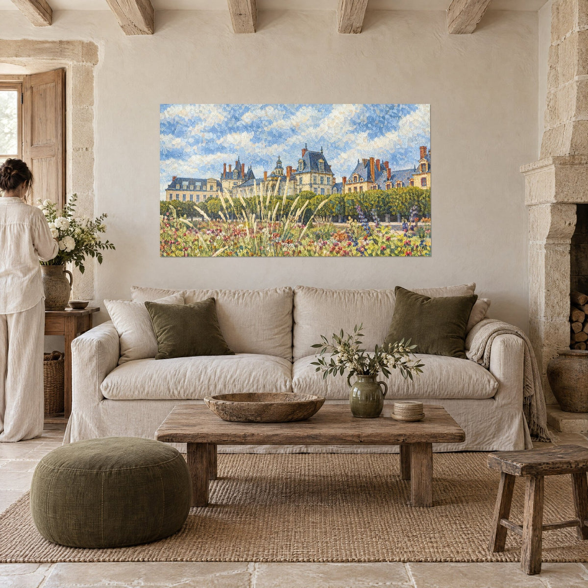 Gemälde Schloss mit blaugrauen Schieferdächern und sandbeigen Fassaden hinter blühenden Gräsern, über einem Sofa in einem hellen Wohnzimmer