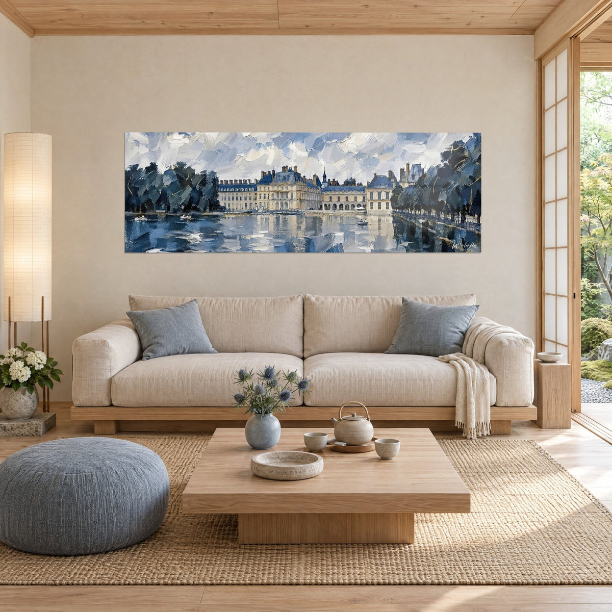 Gemälde Schloss Fontainebleau mit blau schiefergedeckten Dächern, gespiegelt in einem Teich, bewölkter Himmel, über einem Sofa in einem hellen Wohnzimmer