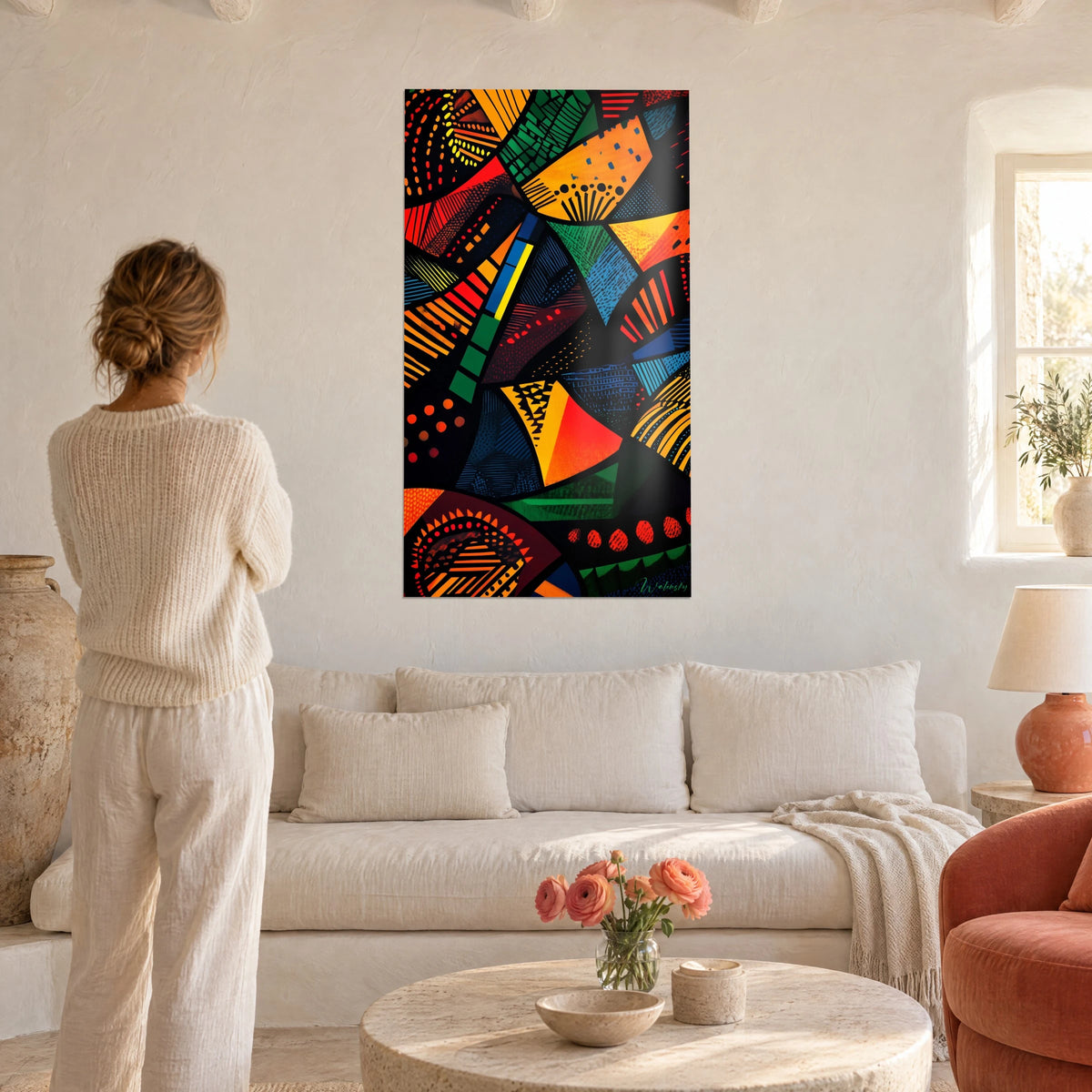 Gemälde mit afrikanischem Mosaik in geometrischen Mustern in Orange, Grün und Rot, eine Frau von hinten über einem Sofa in einem hellen Wohnzimmer