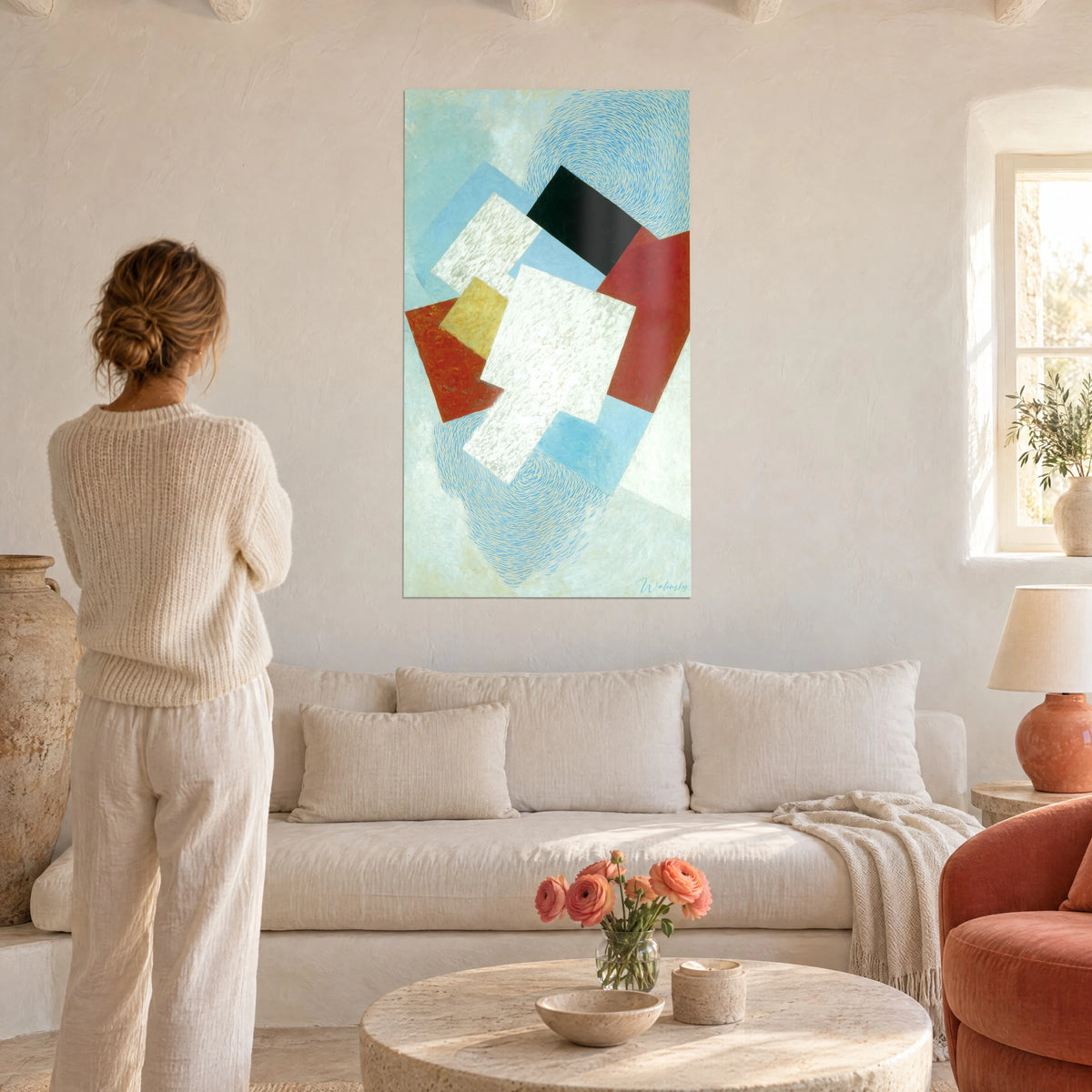 Tableau rectangles superposés blanc nacré, rouge brique et noir sur fond bleu ciel, femme de dos, au-dessus d'un canapé dans un salon lumineux