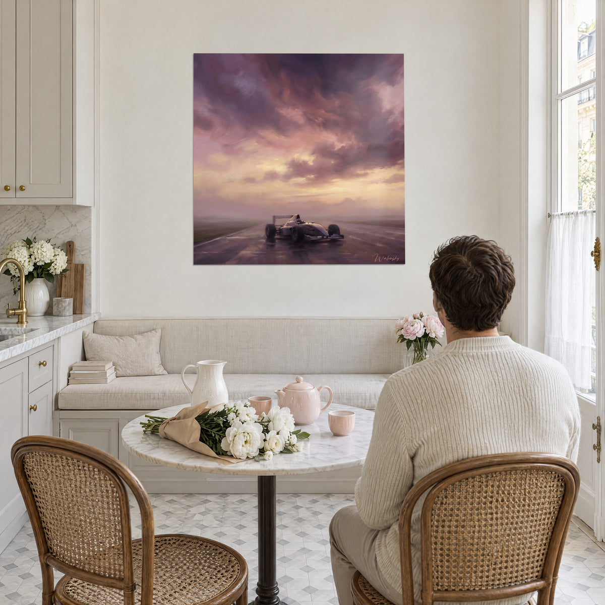 Wall art of a silver single-seater under a pink and purple storm, golden haze on the horizon, in front of a couple seated at a table in a bright kitchen