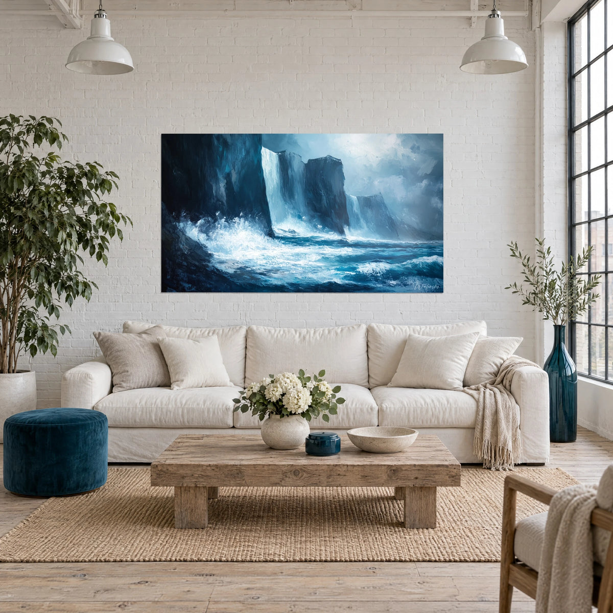 Tableau falaises sombres battues par l'écume blanche, bleu nuit et turquoise, au-dessus d'un canapé dans un salon lumineux