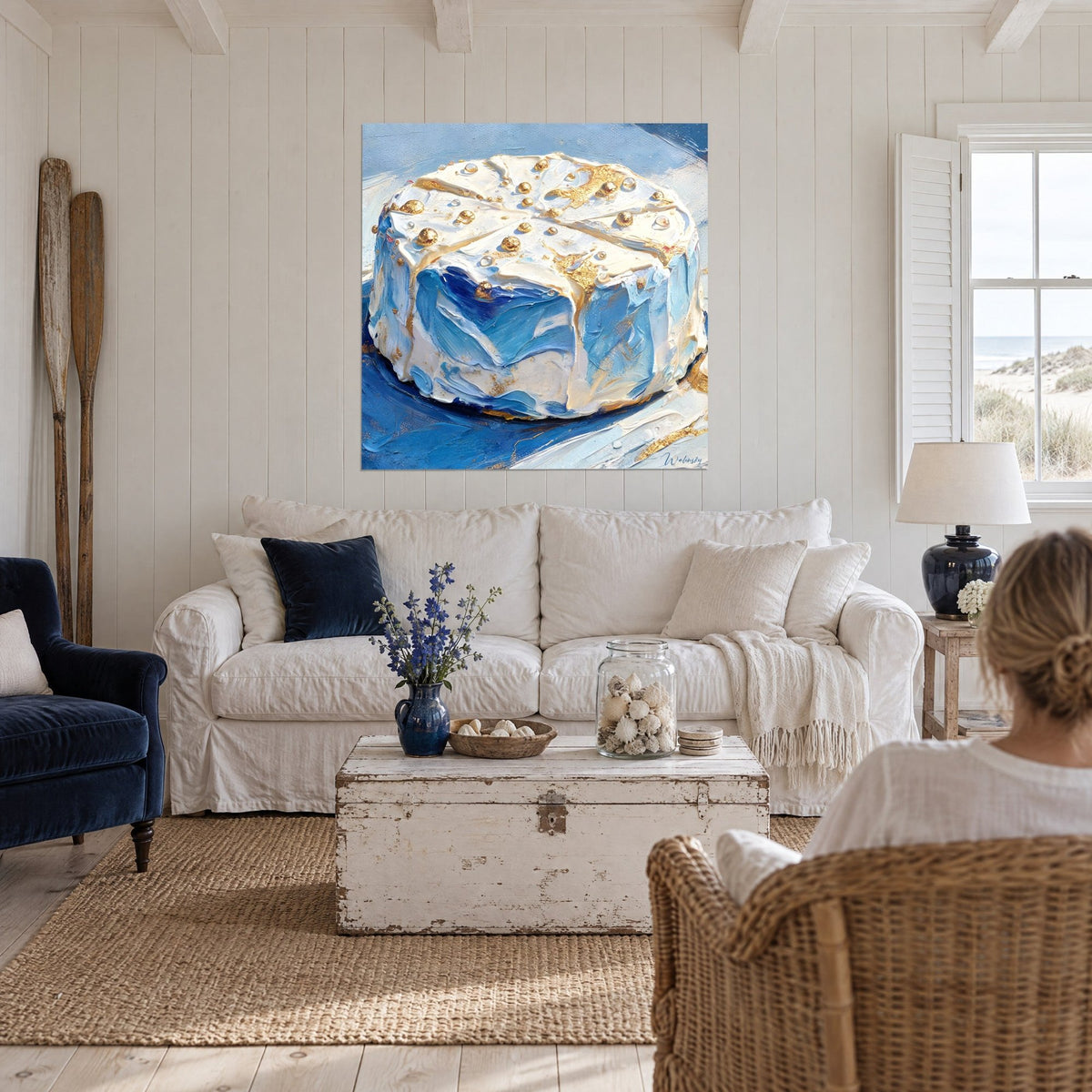 Tableau meule de fromage crème nappée de bleu cobalt et de perles dorées, deux personnes de dos, au-dessus d'un canapé dans un salon lumineux