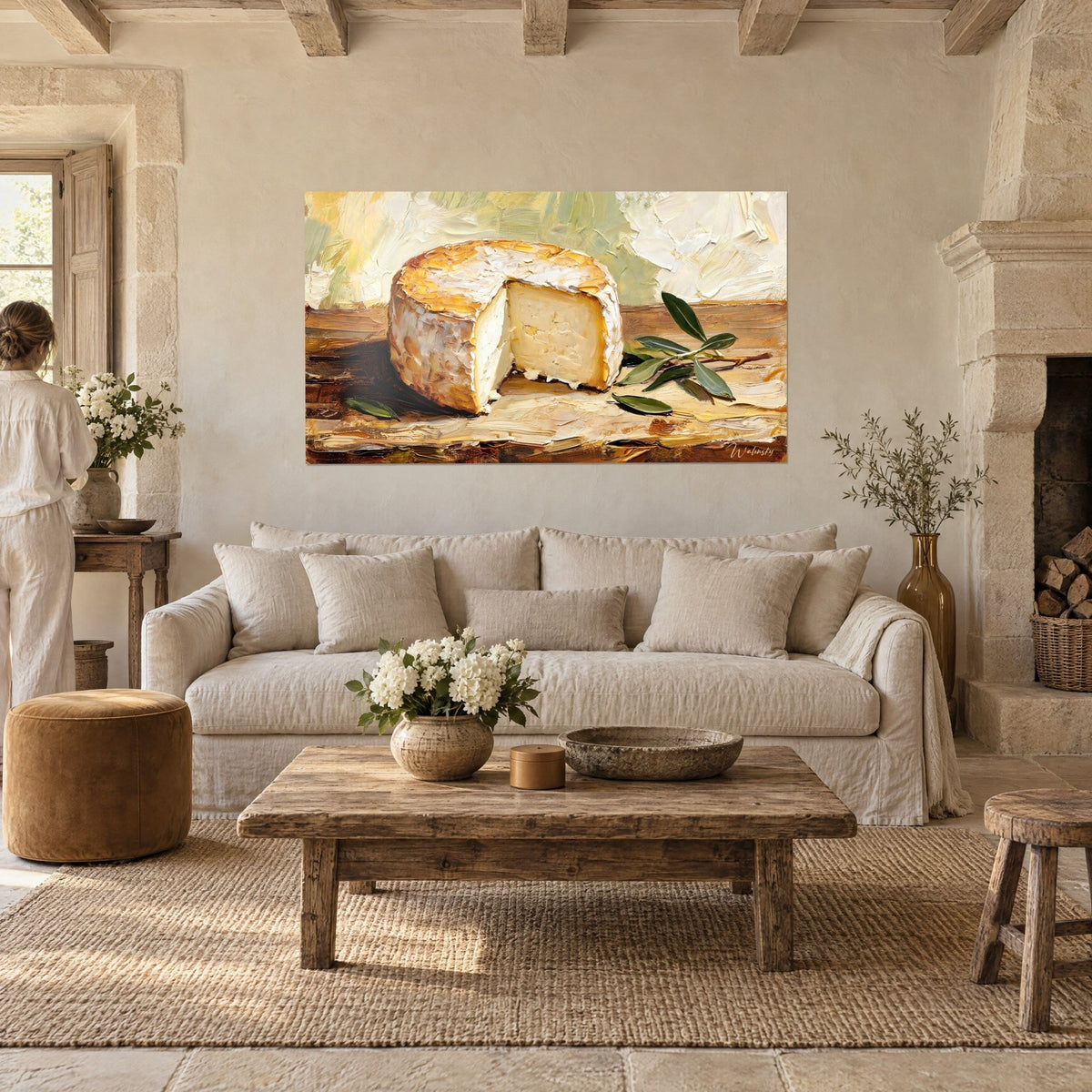 Tableau meule de fromage crémeuse entamée, croûte dorée et blanche près d'un rameau d'olivier vert, au-dessus d'un canapé dans un salon lumineux
