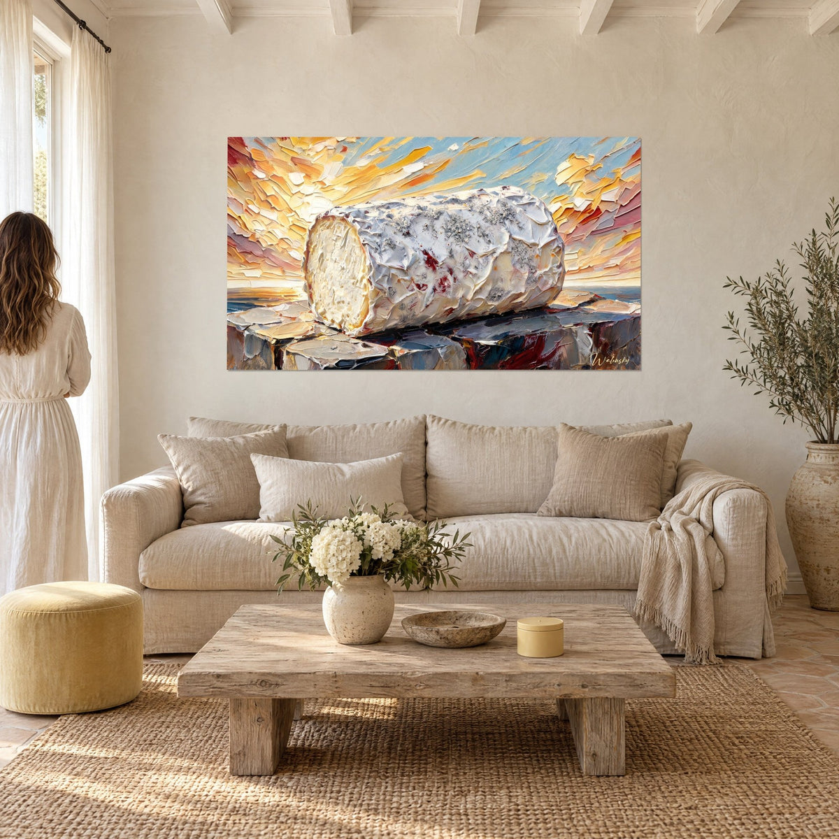 Tableau bûche de chèvre à croûte cendrée, empâtements gris et blanc sur ciel orangé, au-dessus d'un canapé dans un salon lumineux