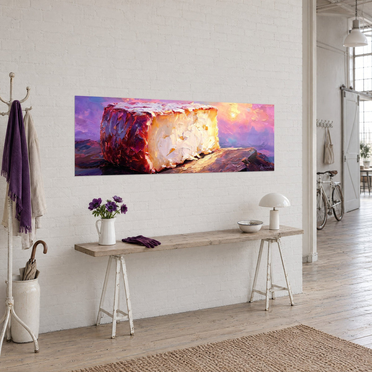 Cuadro Rueda de queso marfil con corteza granate, cielo malva y dorado, en una pared blanca junto a una consola de madera