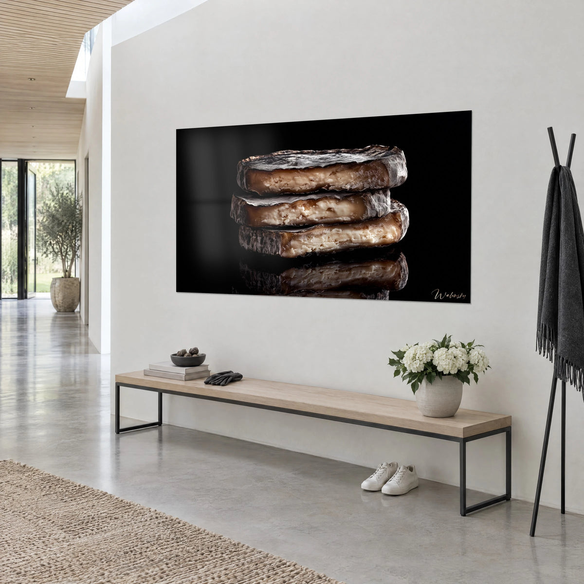 Wall art stack of aged cheeses, silvery rind and creamy heart marbled with brown, deep black background, hung above a light wood bench, Walensky