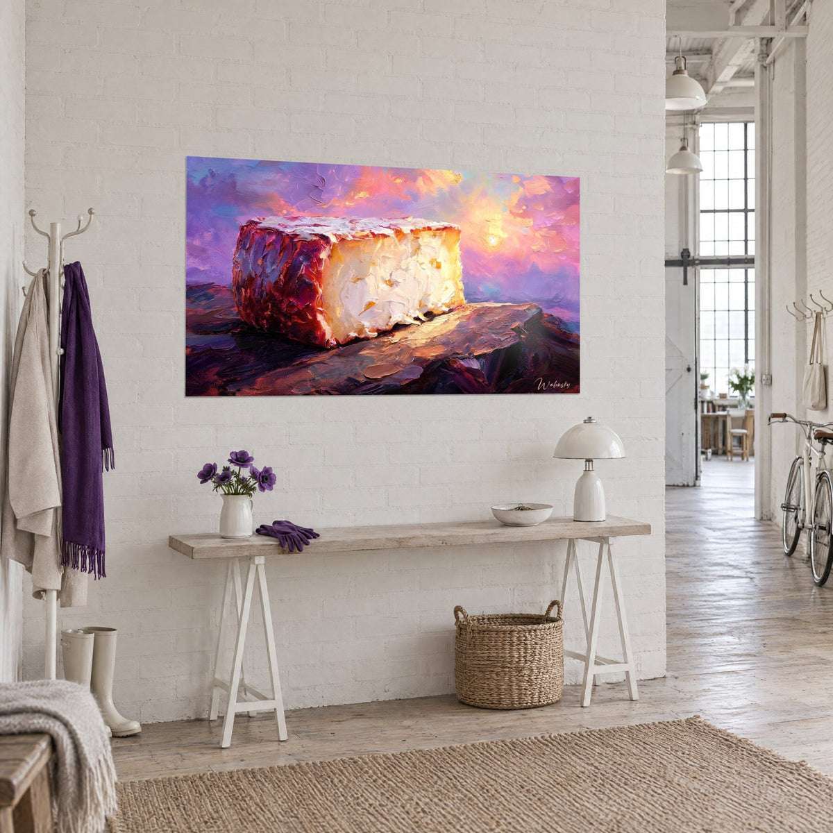Tableau meule de pâte molle aux reflets dorés sur plateau violet, nuages orange, accroché dans un loft d'artiste en briques blanches