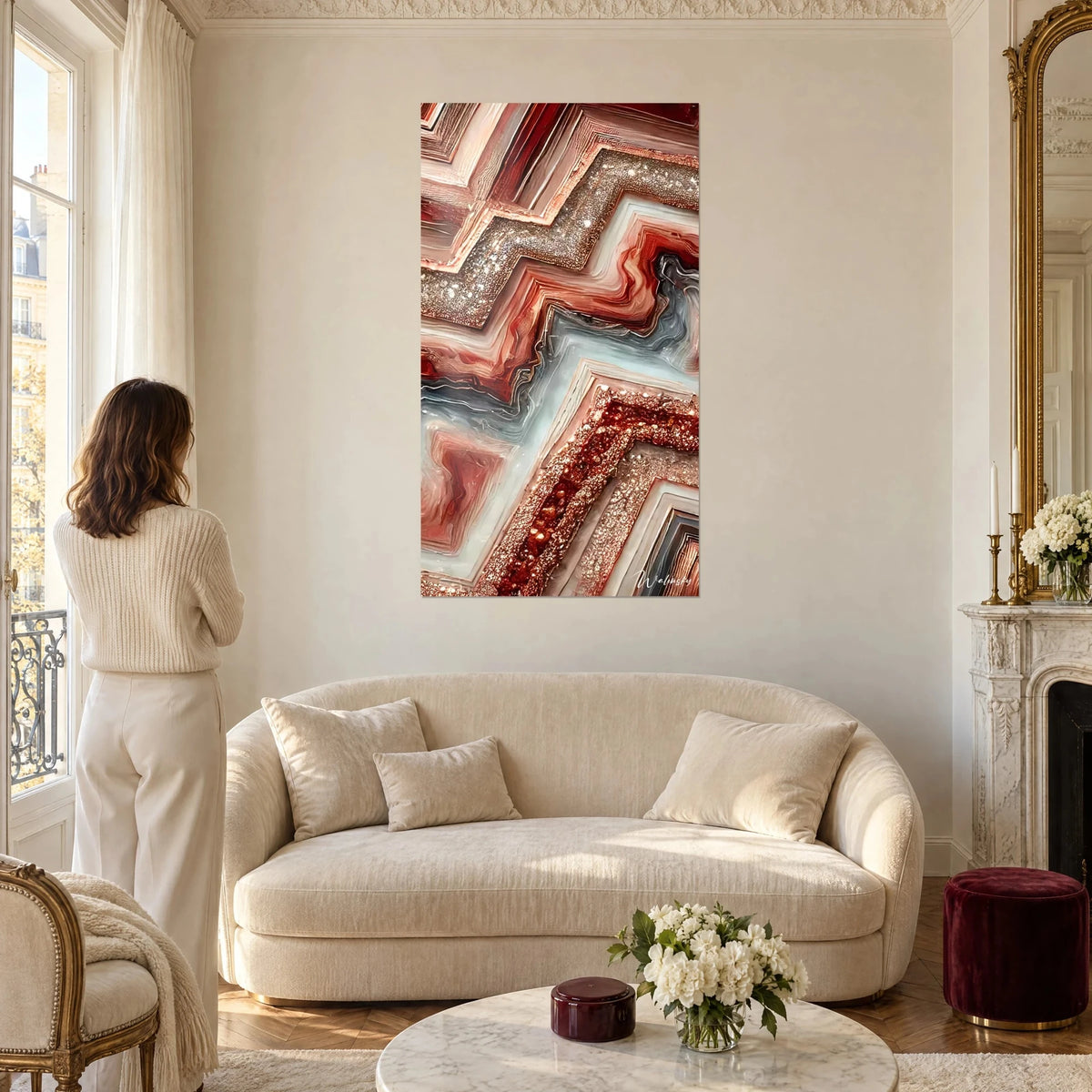 Schilderij met geometrisch agaatpatroon in roestkleurige chevrons en koperkleurige glitteraccenten, vrouw van achteren, boven een bank in een lichte woonkamer