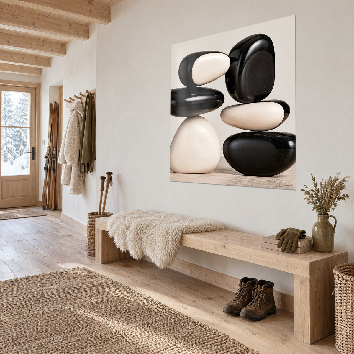 Wall art of stacked polished stones, glossy black and cream white, beside a light wood bench and a sheepskin rug