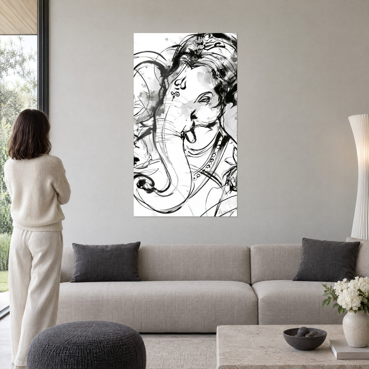 Wall art elephant in black ink, curled trunk and bold forehead on white background, hanging above a sofa in a bright living room