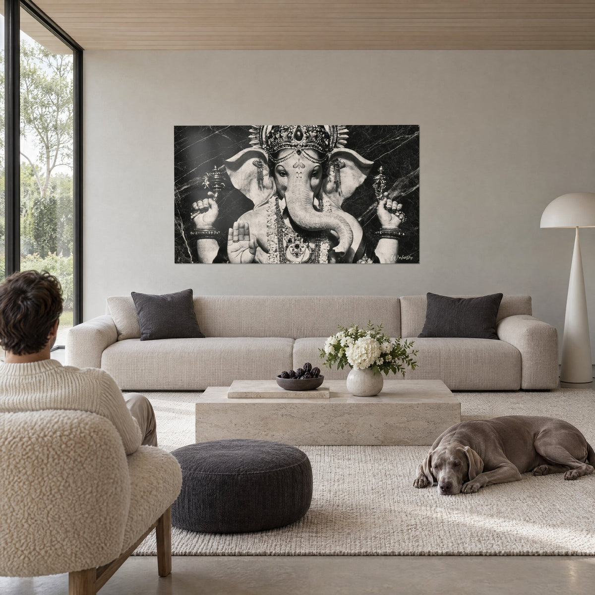 Schilderij Ganesh in zwart-wit gebeeldhouwd, opgerolde slurf, gecisineerde kroon tegen een gemarmerde achtergrond, boven een bank in een lichte woonkamer