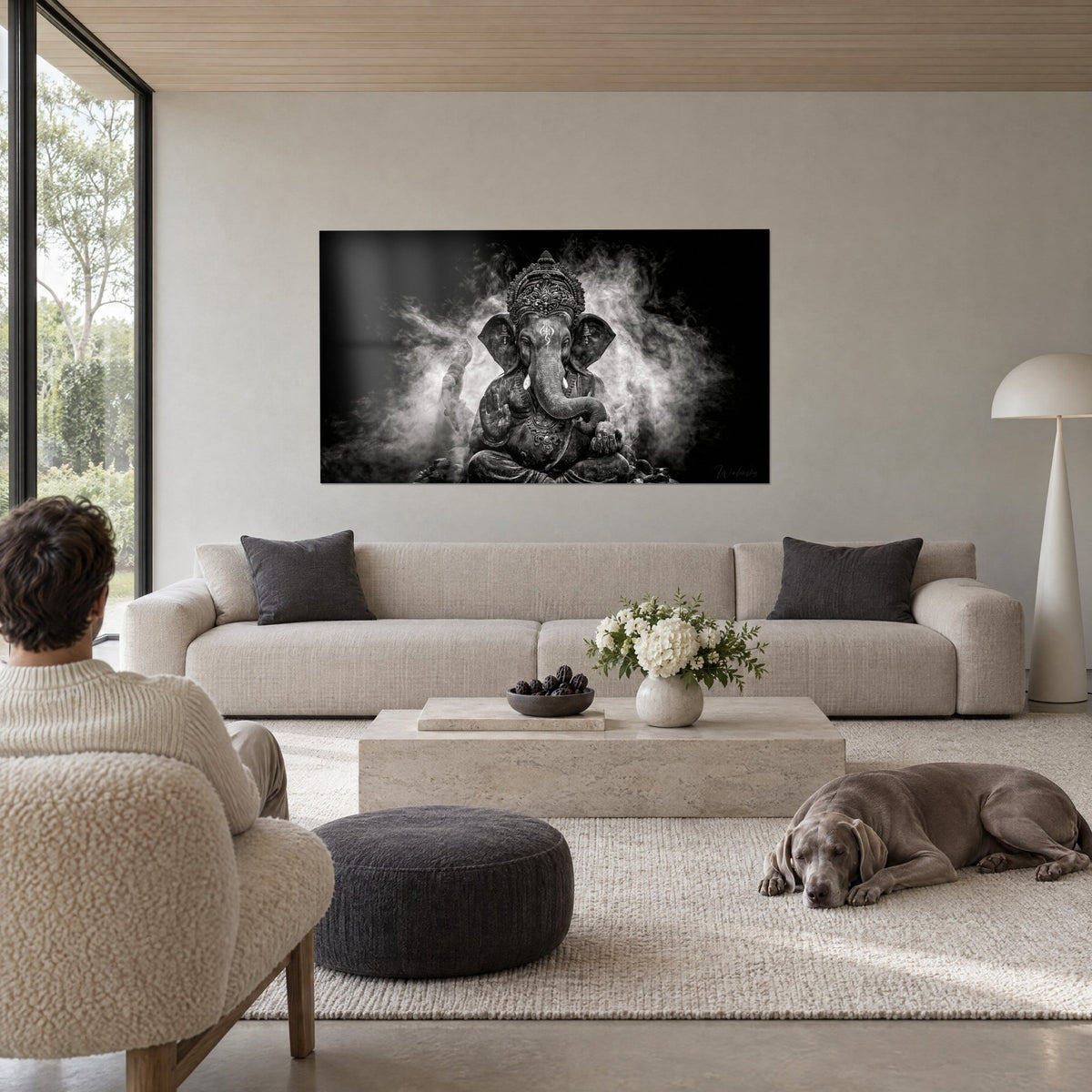Wall art Ganesh in black and white, curled trunk, chiselled crown, grey smoke forming a halo, above a sofa in a bright living room