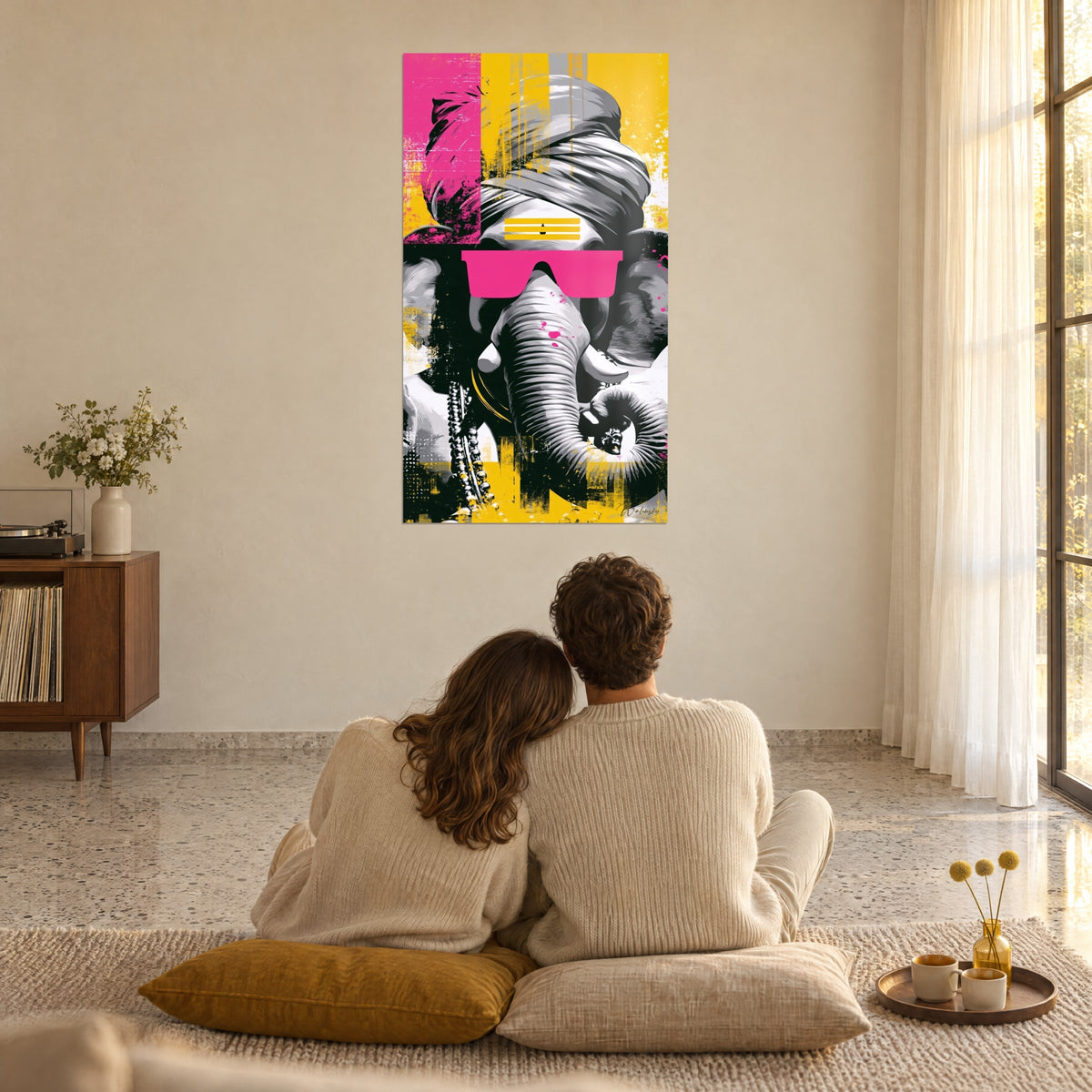 Wall art sacred elephant in black, grey and yellow, fuchsia glasses, in a light-filled living room, two people seated on cushions