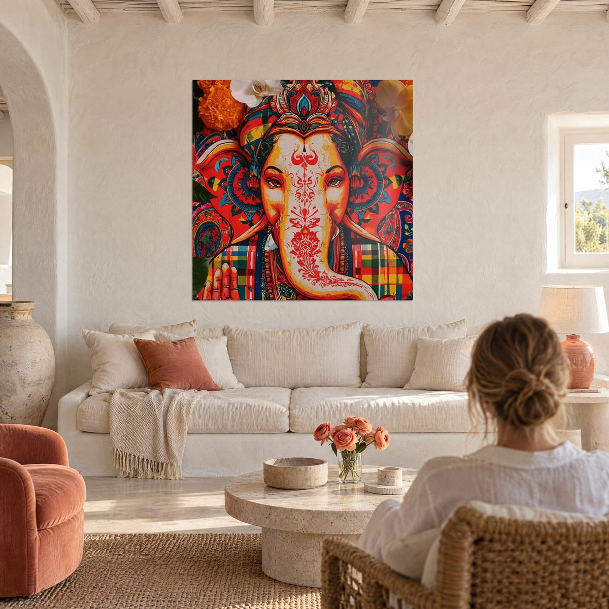Wall art Ganesh with a trunk adorned with a red lotus, yellow and blue turban, above a sofa in a bright living room