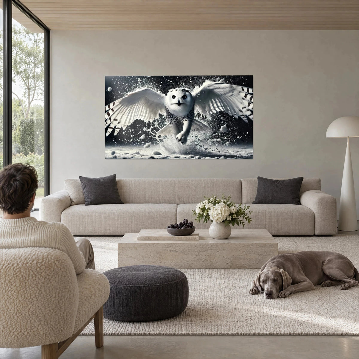 Wall art snowy owl with wings spread in a cloud of snow, black and white, above a sofa in a bright living room