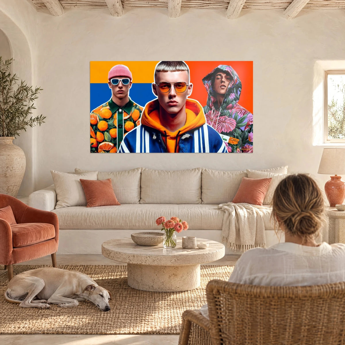 Tableau trio de mannequins streetwear, bonnet rose et sweat orange sur fond bleu, au-dessus d'un canapé dans un salon lumineux