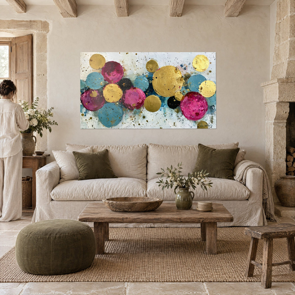 Wall art with gold and magenta circles splashed with paint, on a textured white background, above a sofa in a bright living room