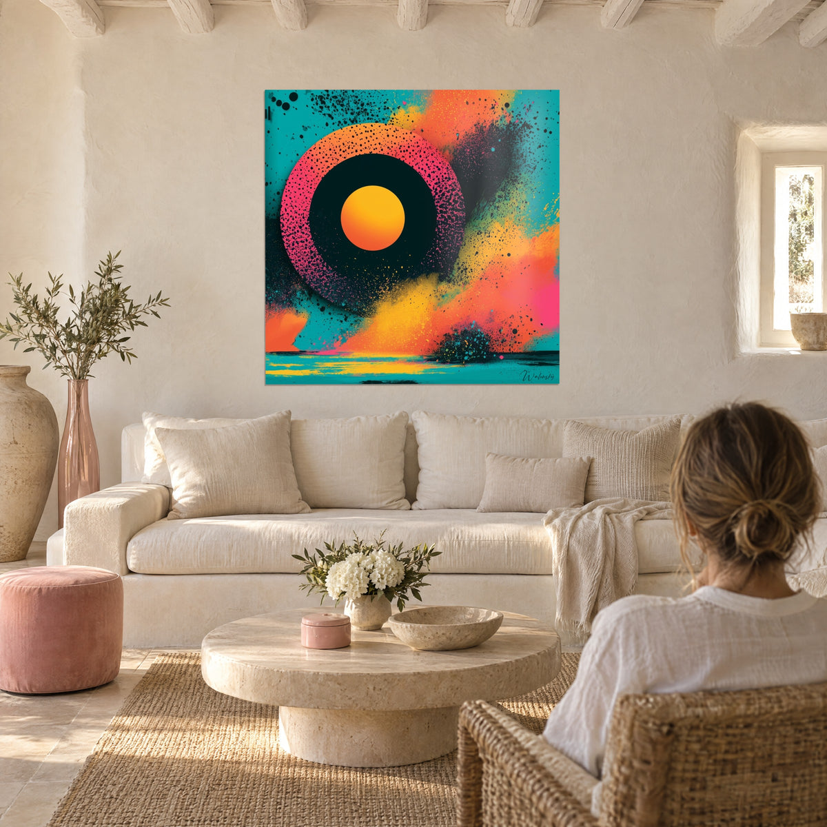 Schilderij oranje schijf omringd door een roze ring met zwarte spikkels, turquoise spatten, boven een bank in een lichte woonkamer