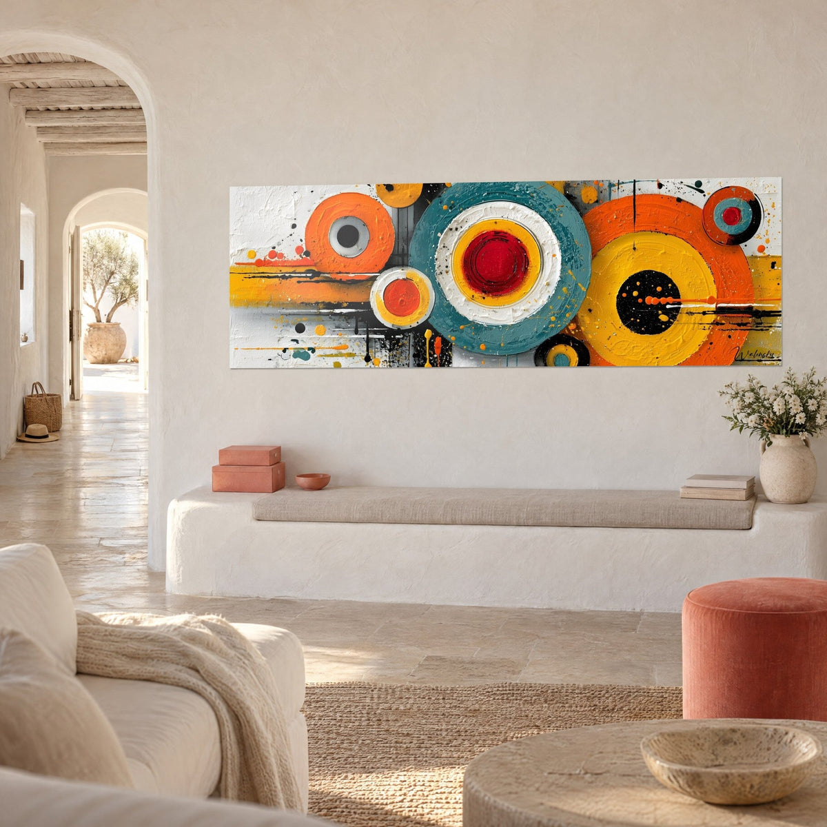 Cuadro discos amarillo mostaza y turquesa salpicados de negro, corazón carmín, visto de tres cuartos sobre una pared blanca de casa mediterránea