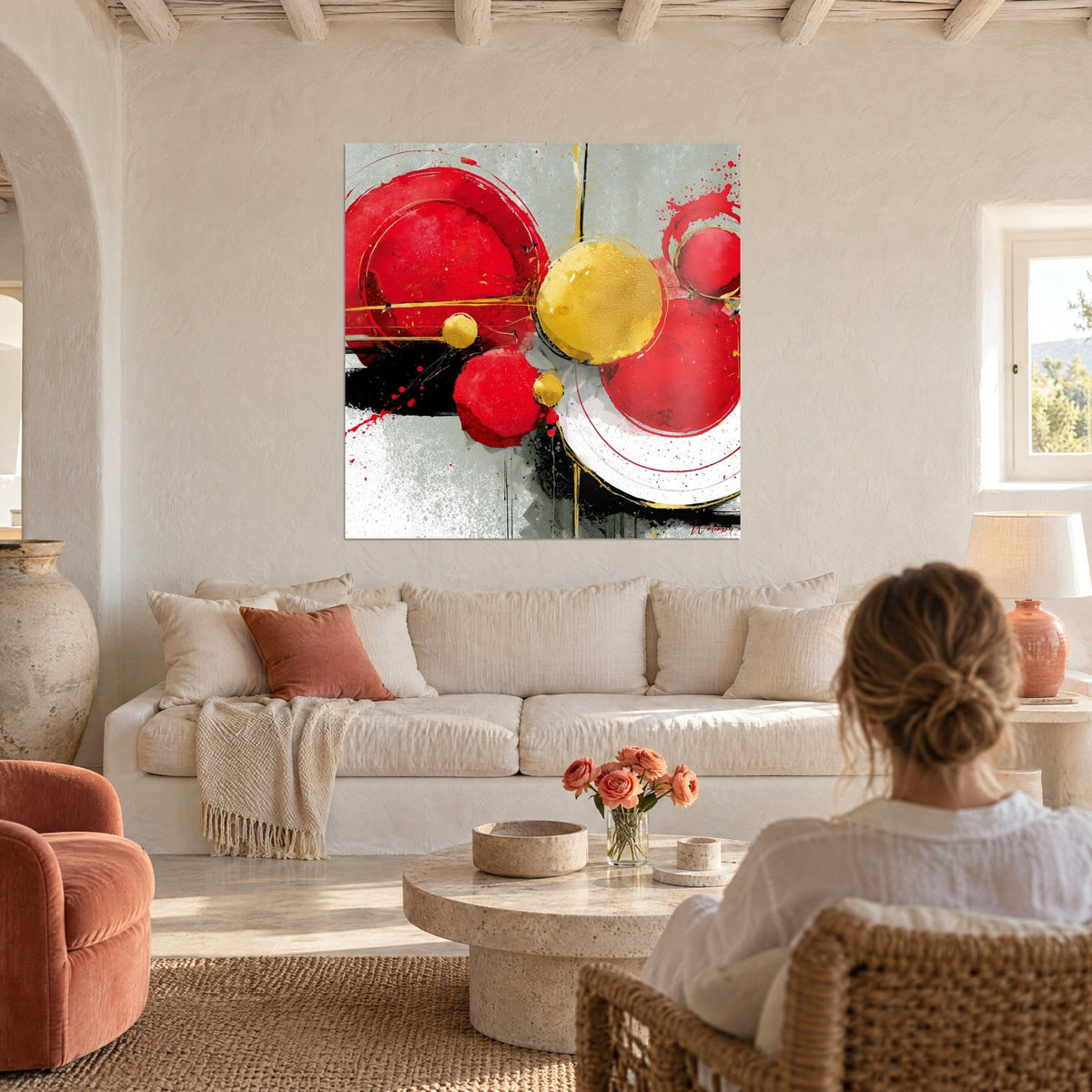 Tableau cercles rouge vif et jaune doré éclaboussés, une femme de dos au-dessus d'un canapé dans un salon lumineux