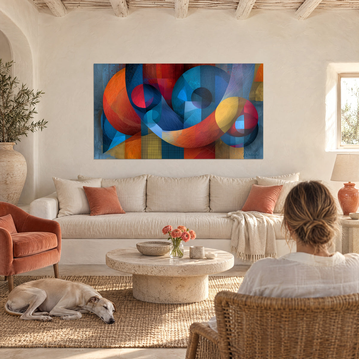 Quadro con cerchi blu e nastri arancio intrecciati, rosso vivo e giallo, una donna con il suo levriero, appeso sopra un divano in un soggiorno luminoso