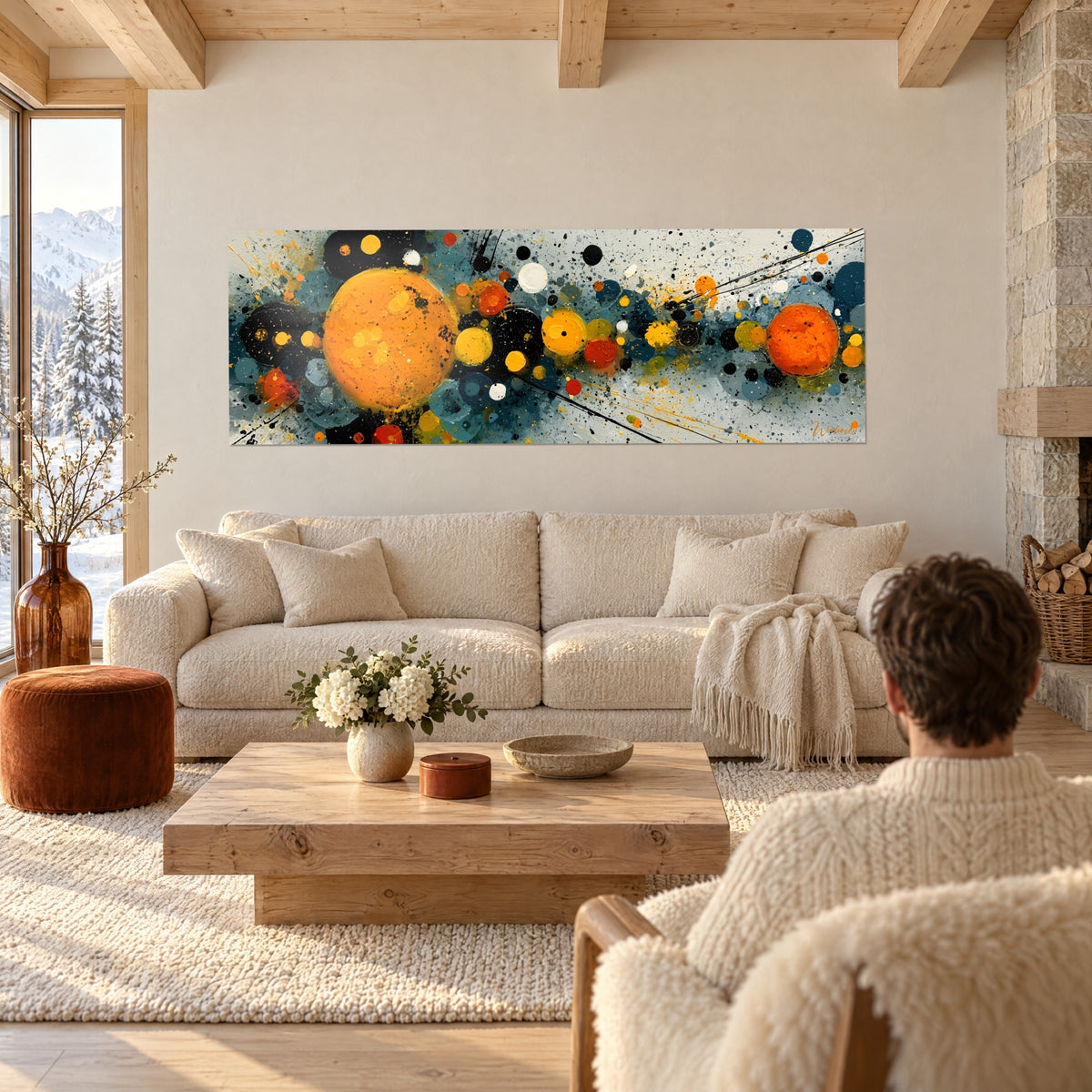 Tableau sphères ocre éclatées sur fond bleu pétrole, regardé par un homme de dos, au-dessus d'un canapé dans un salon lumineux
