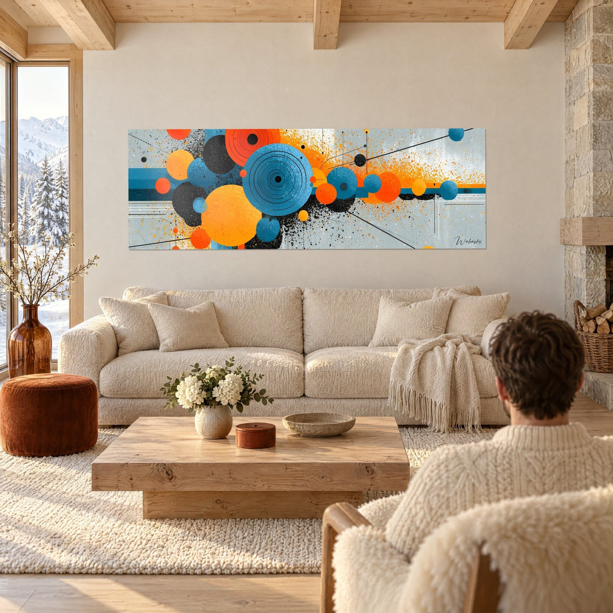 Tableau cercles concentriques bleus et orange éclatés, éclaboussures noires sur fond gris perle, au-dessus d'un canapé dans un salon lumineux