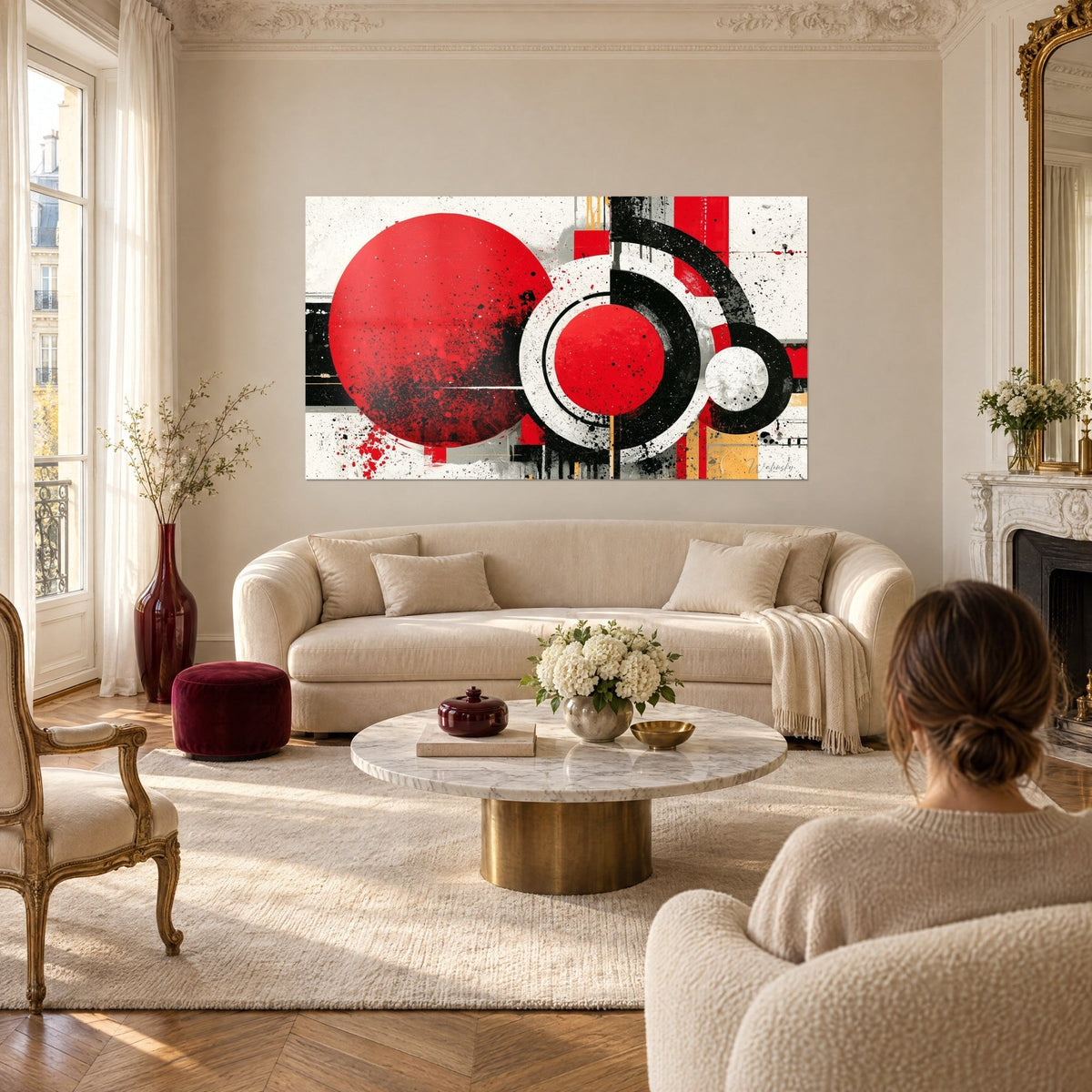 Gemälde scharlachrote Scheibe mit schwarzen Spritzern und weißen Ringen auf cremefarbenem Grund, Frau von hinten, über einem Sofa in einem hellen Wohnzimmer