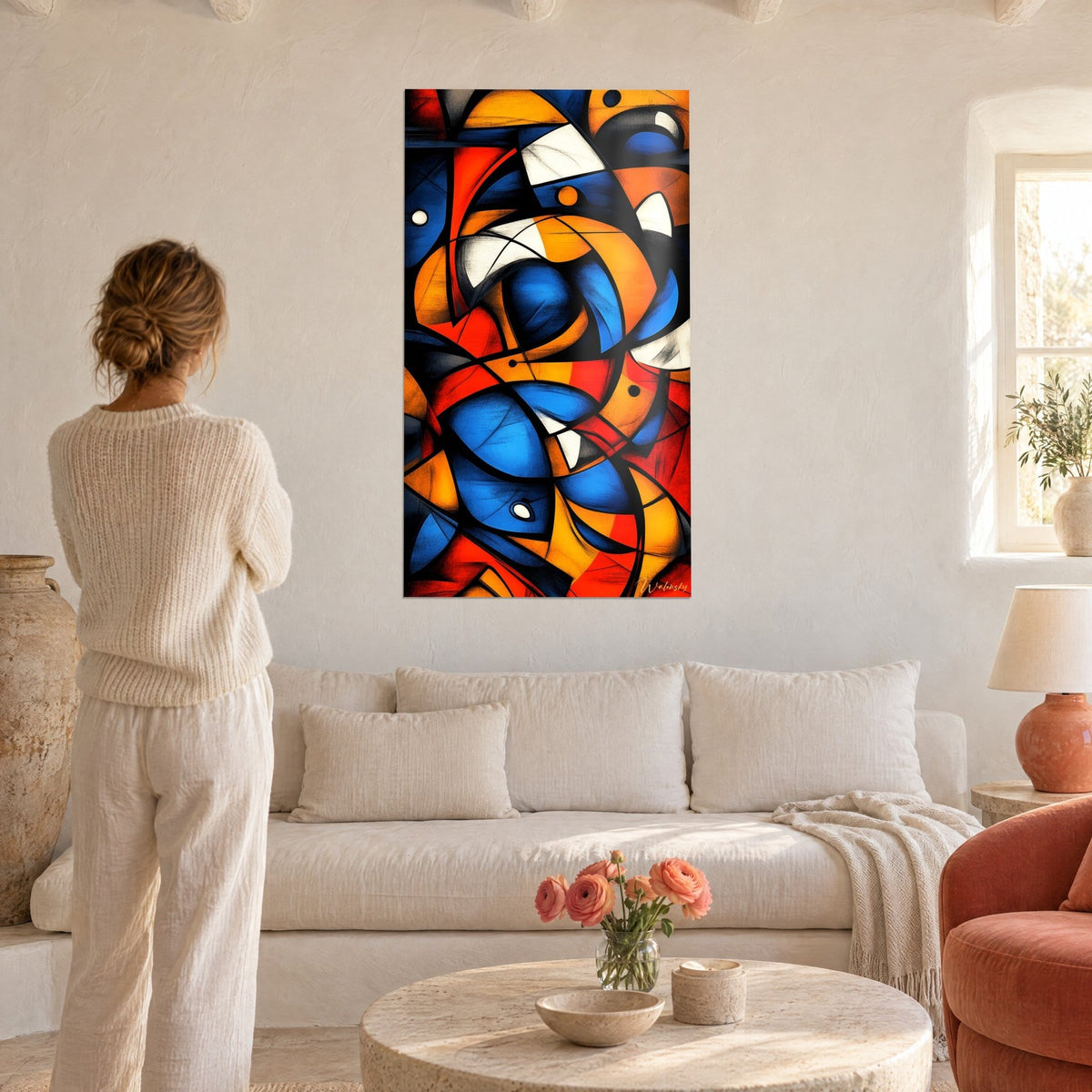 Tableau mosaïque cubiste bleu cobalt et orange safran entre traits noirs, femme de dos, au-dessus d'un canapé dans un salon lumineux