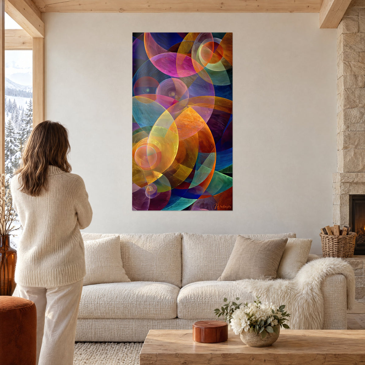 Wall art with overlapping translucent orange, pink and yellow circles, woman seen from behind, above a sofa in a bright living room