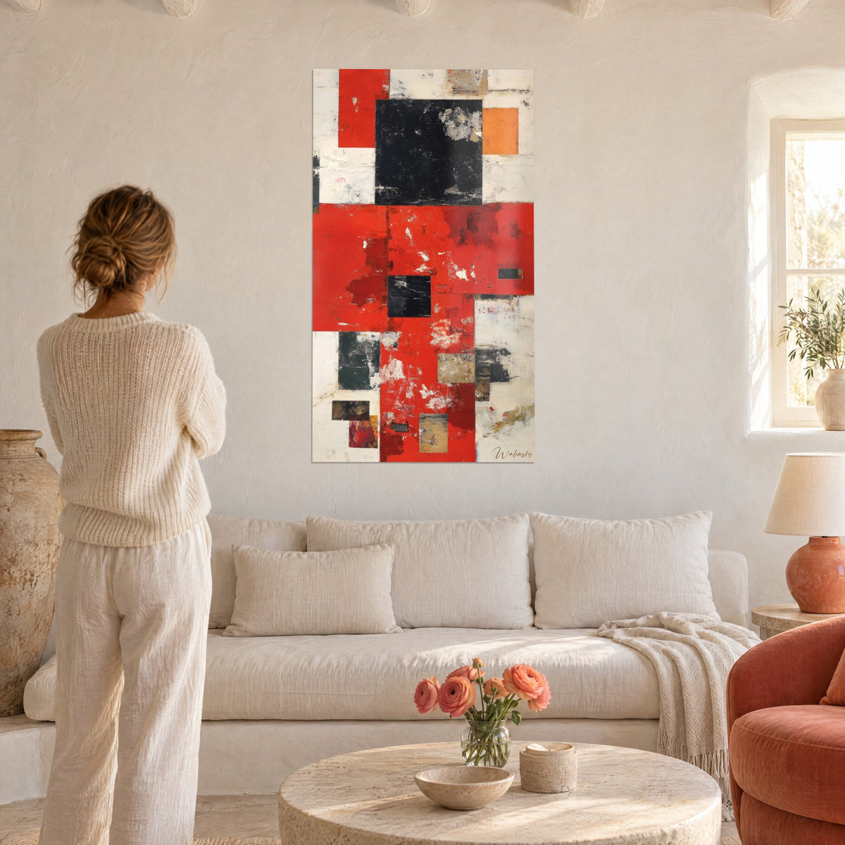 Tableau abstraction géométrique rouge vif aux carrés noirs et ocre, une femme de dos, au-dessus d'un canapé dans un salon lumineux