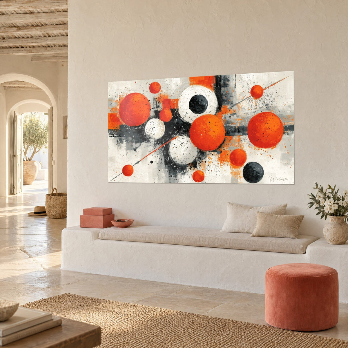 Wall art with flame-orange and charcoal circles in a grey paint burst, angled view of a cream wall, white bench and rust-coloured pouf