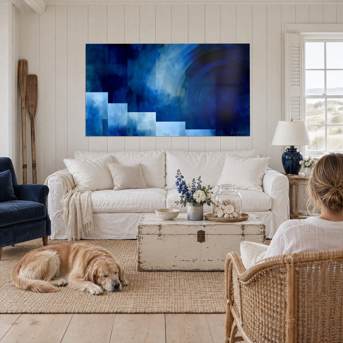 Wall art stepped squares in sky blue under an indigo arch, couple seen from behind with a retriever, above a sofa in a bright living room