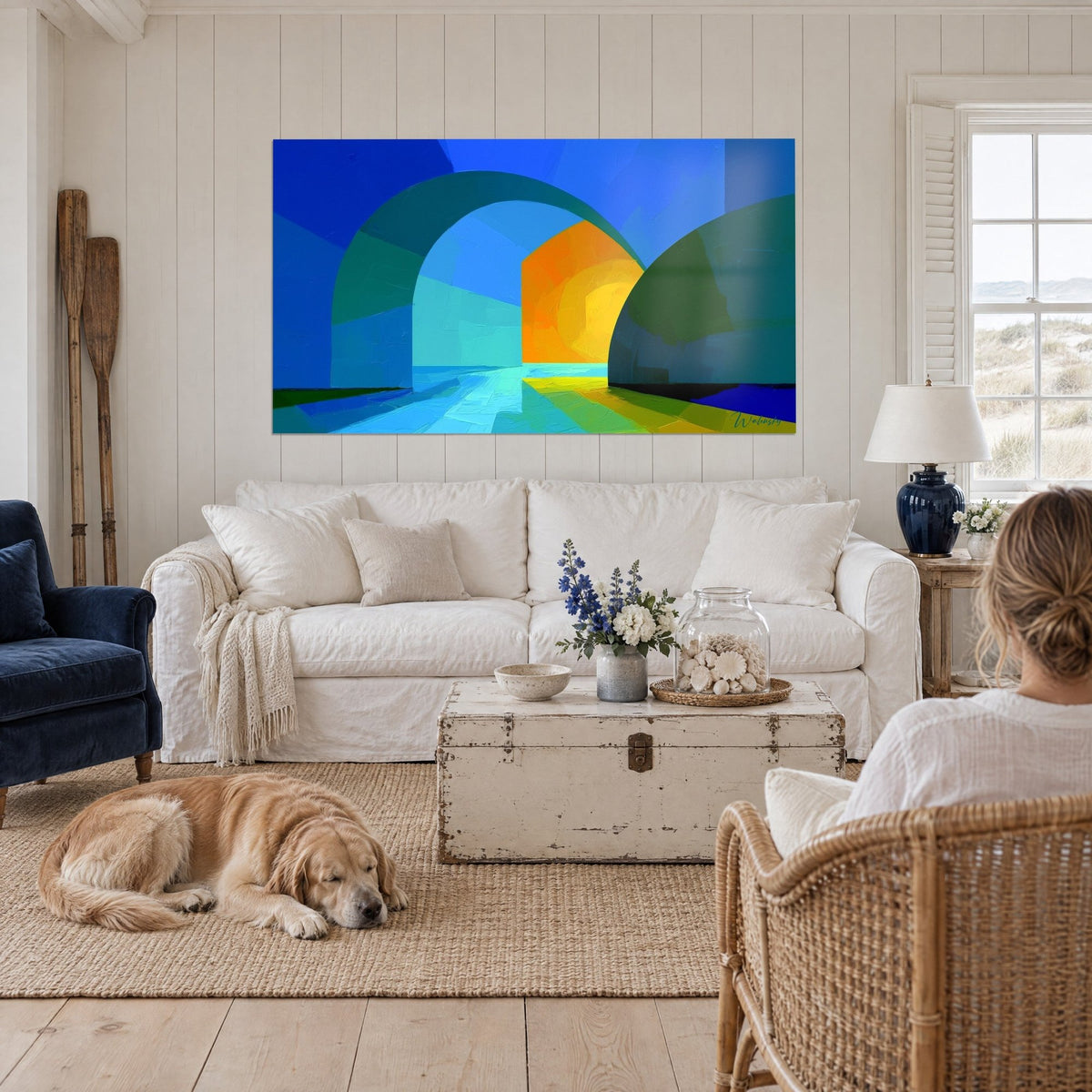 Gemälde mit kobaltblauen Bögen, die sich zu einem safranorangen Licht öffnen, über einem Sofa in einem hellen Wohnzimmer