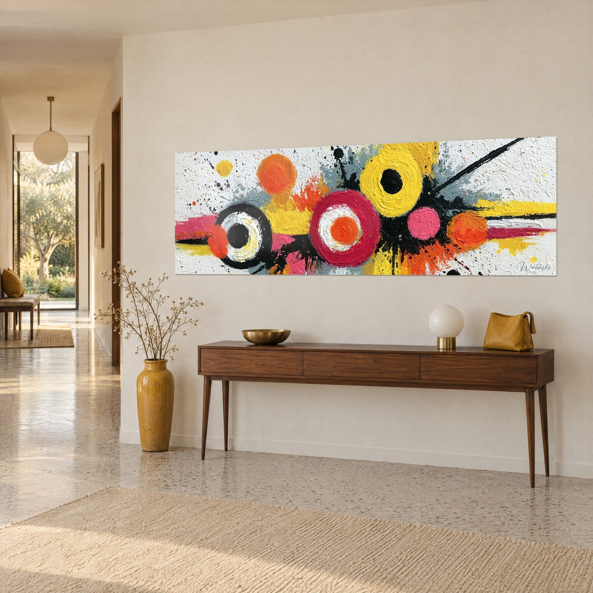 Wall art with a geometric explosion of orange and crimson discs on a textured white background, three-quarter view, above a wooden console