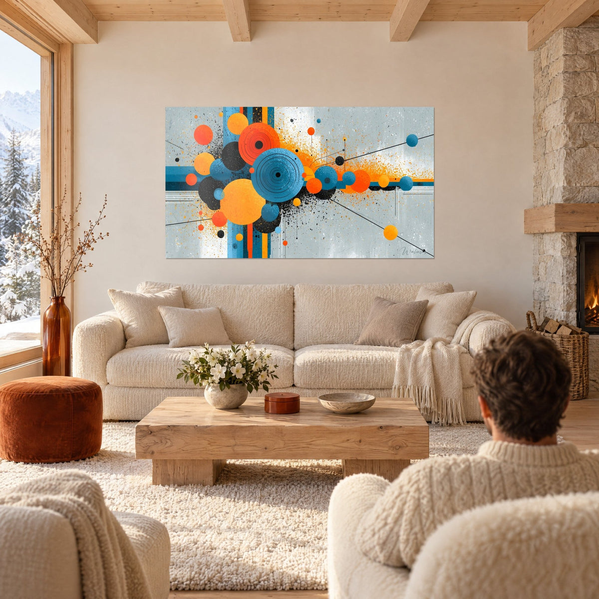 Wall art of concentric blue and orange circles splashed with black, grey background, man seen from behind, above a sofa in a bright living room