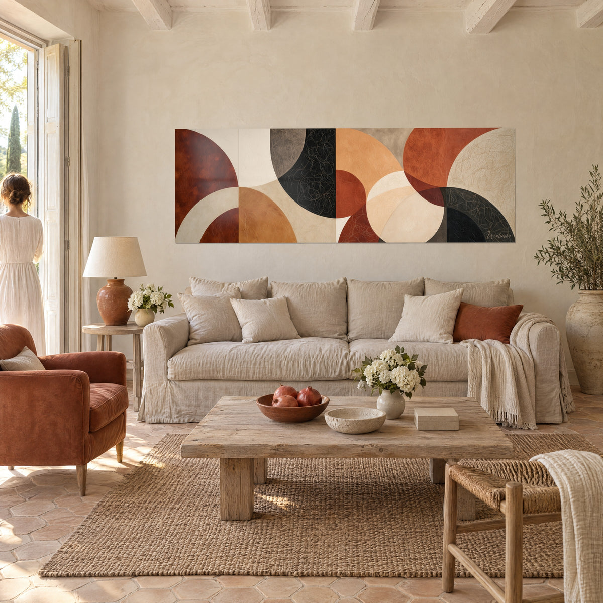 Πίνακας με γεωμετρικά ημικύκλια σε terracotta, μαύρο και ώχρα, βλέπει μια γυναίκα από την πλάτη, πάνω από ένα καναπέ σε ένα φωτεινό σαλόνι