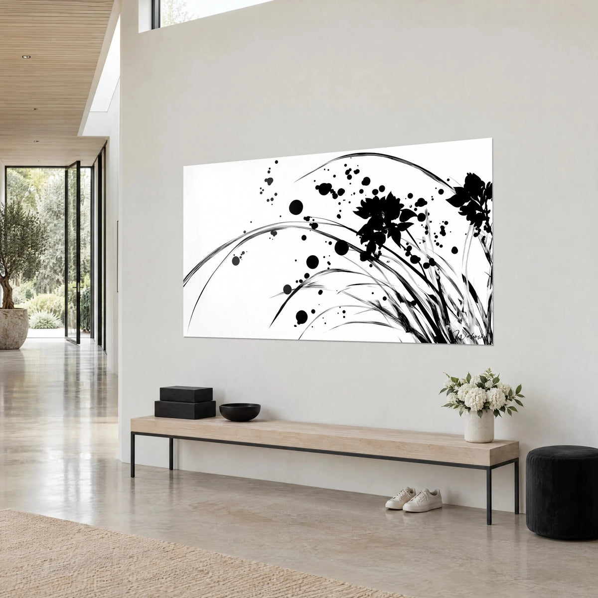 Wall art of a black ink flower silhouette and arching stems on bright white, light beige walls, wooden bench, three-quarter view