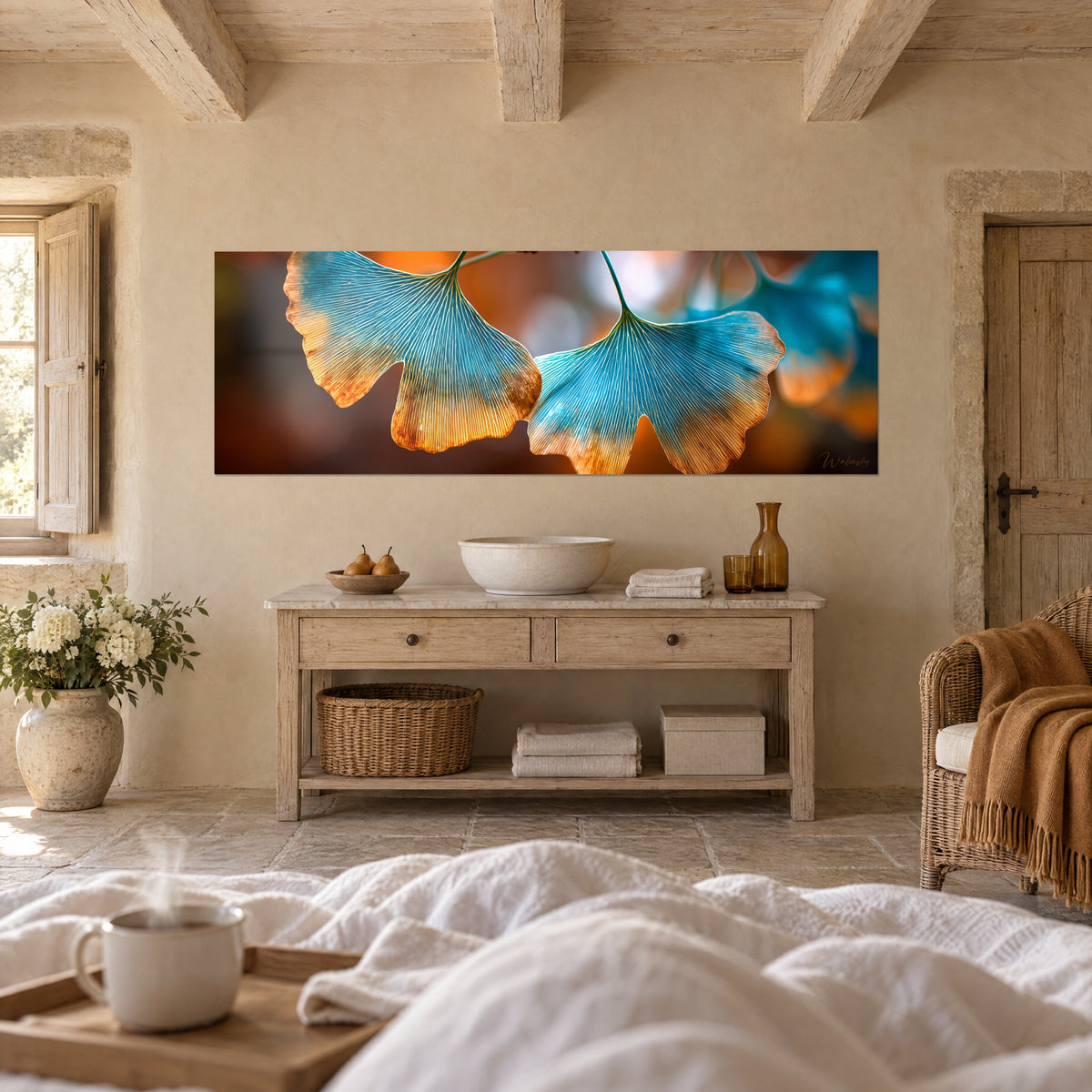 Quadro ventagli di ginkgo dalle nervature finemente tracciate, turchese e arancio vivo, sfondo bokeh marrone, sopra un letto in una camera luminosa