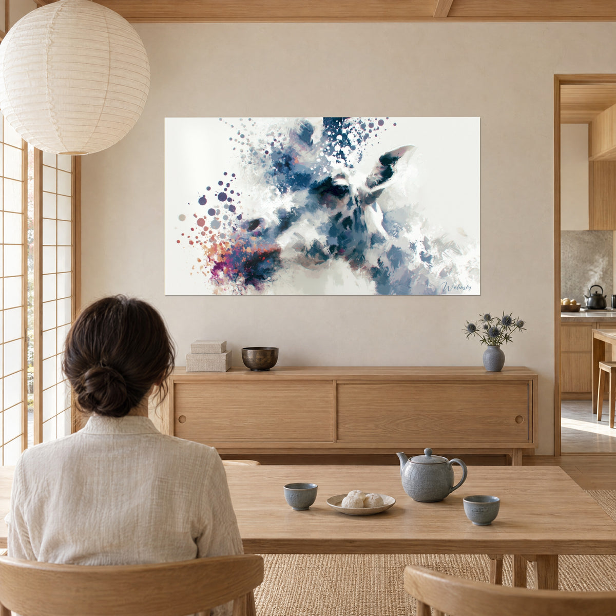 Quadro apparizione di giraffa con pennellate blu ardesia e grigio perla, osservata da una donna con chignon morbido, soggiorno japandi, legno chiaro