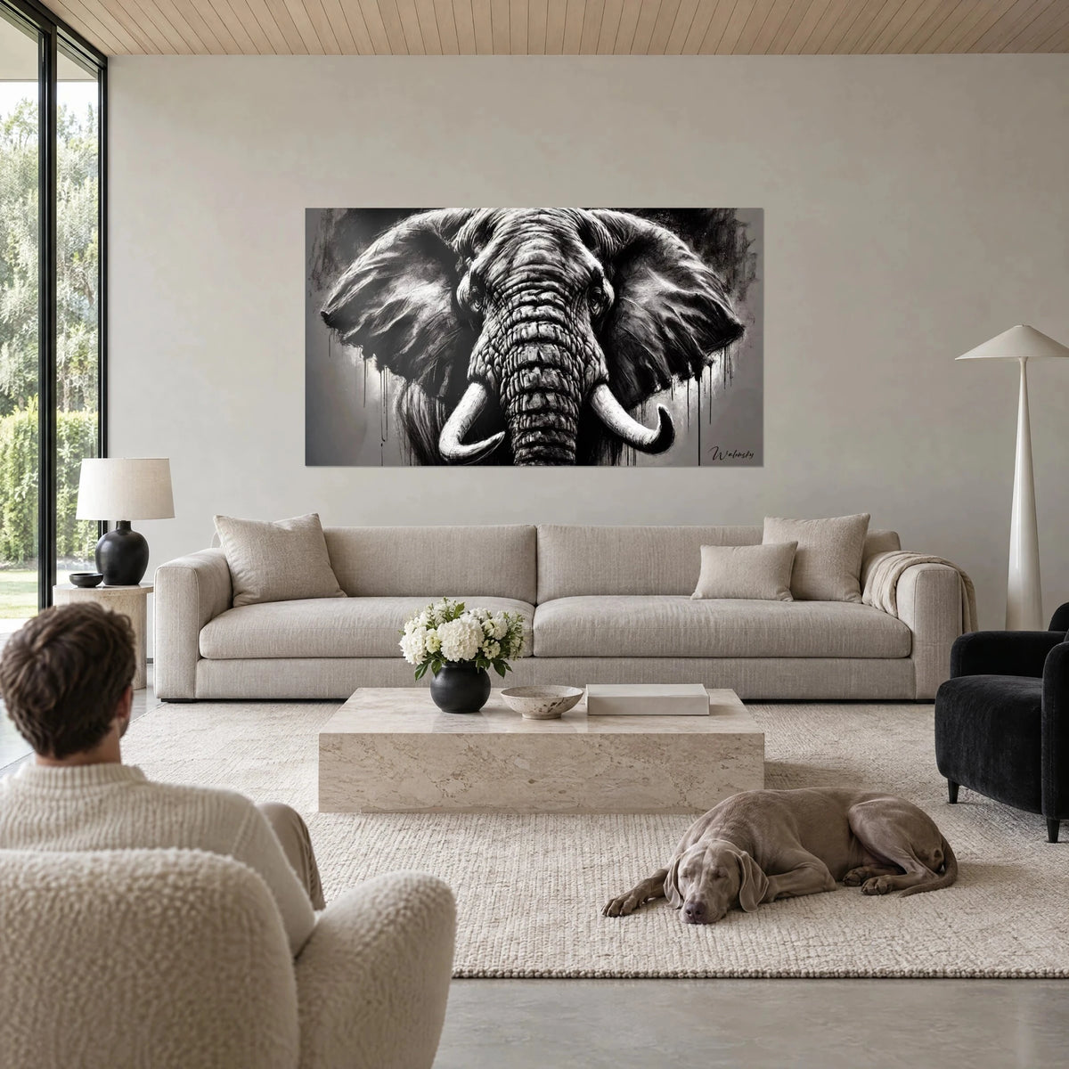 Tableau éléphant d'Afrique de face, défenses ivoire et oreilles charbon, un homme et son Weimaraner au-dessus d'un canapé dans un salon lumineux