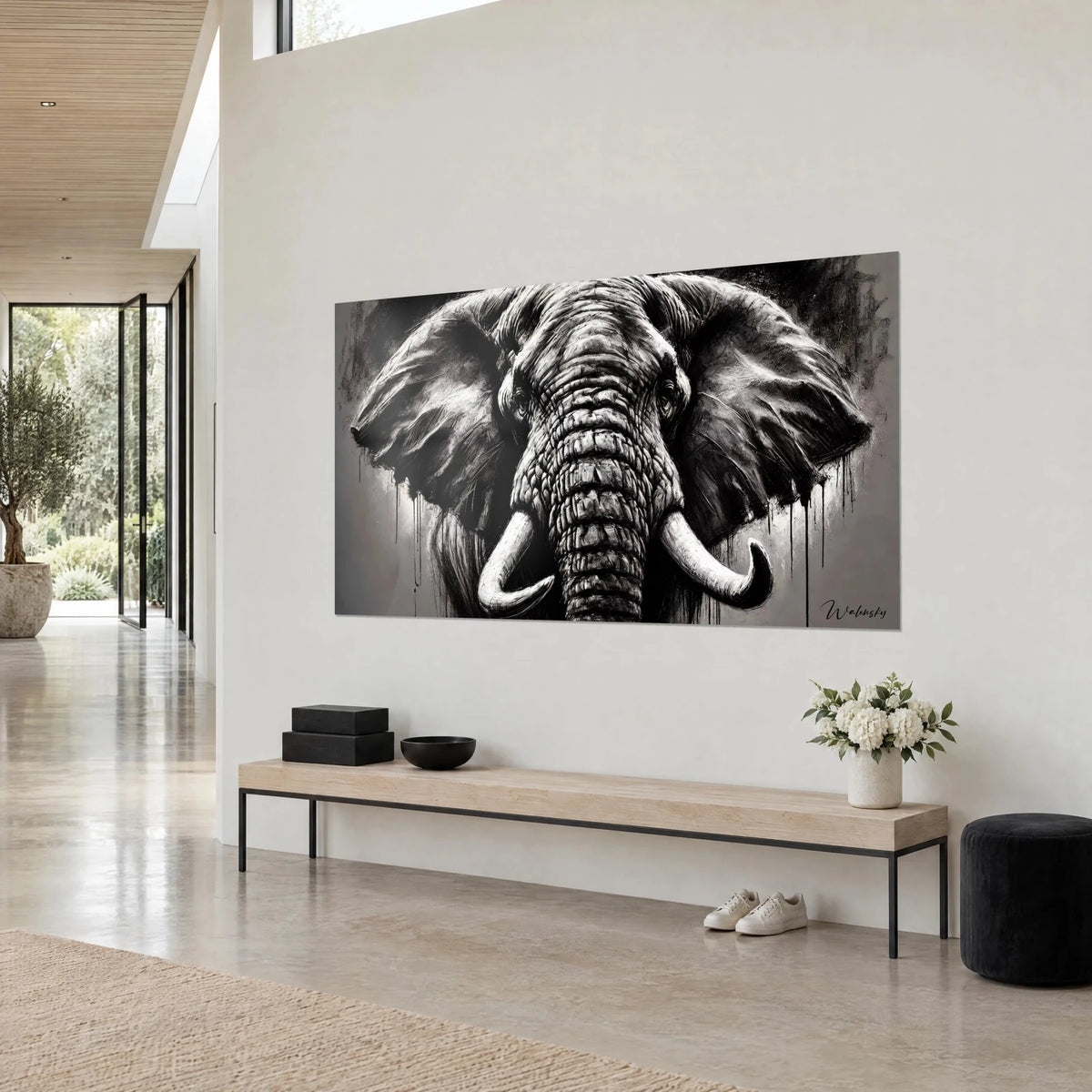 Tableau pachyderme en encre noire et gris perle, trompe ridée, défenses blanches, coulures, vue de trois-quarts sur mur beige près d'un banc en bois
