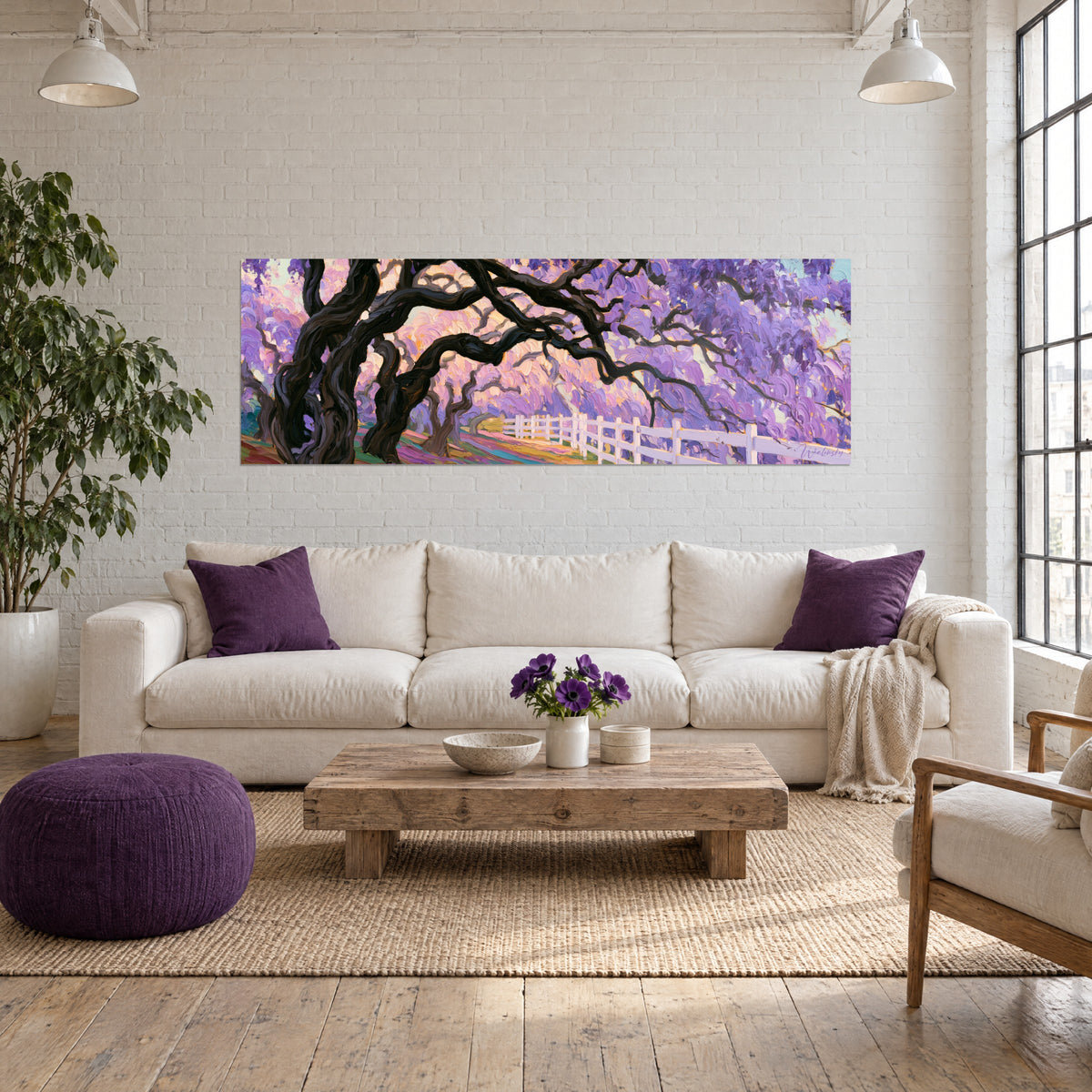 Wall art cascading violet wisteria, gnarled black trunk and white fence, pink and orange background, above a sofa in a bright living room