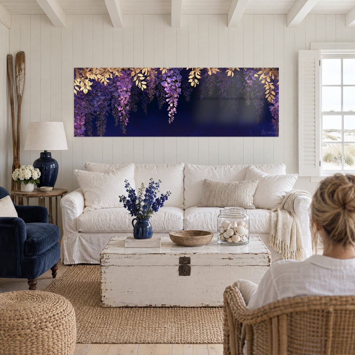 Wall art purple wisteria with gold leaves on midnight blue background, two people seen from behind above a sofa in a bright living room